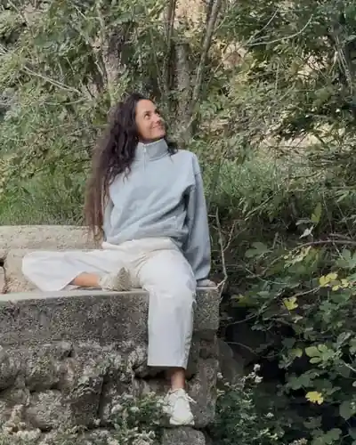 Clarisse assise sur un muret de pierre, au milieu de la verdure